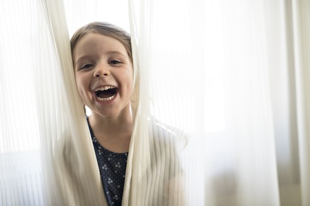 Little beautiful girl on window curtain bedroomの写真素材