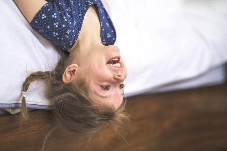 Little beautiful girl on bedroom upside downの写真素材