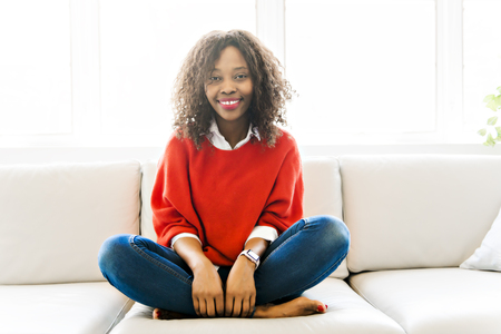 Attractive black young woman relaxing on a sofa at homeの写真素材