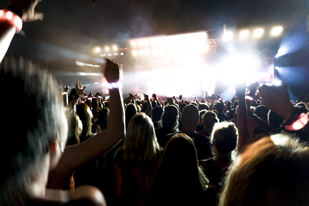 silhouettes of concert crowd in front of bright stage lights.の写真素材