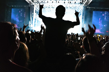 silhouettes of concert crowd in front of bright stage lights.