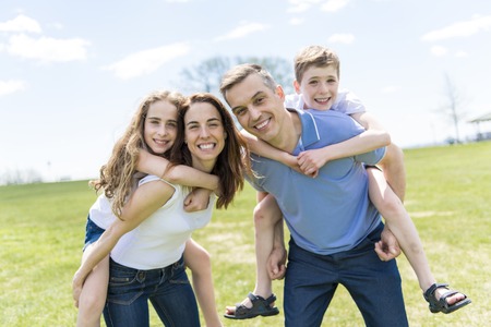 Family of four outdoors in a field having funの写真素材