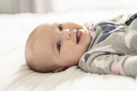 A Cute baby girl on a white bed at home