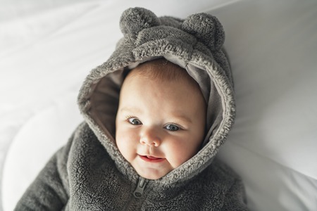 A Cute baby girl on a white bed at homeの写真素材
