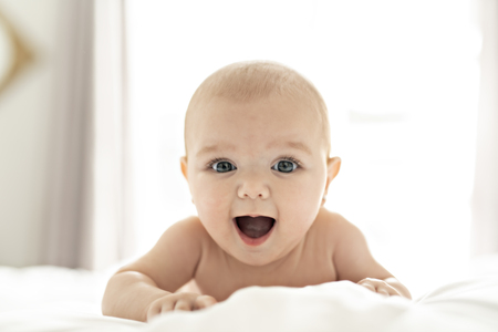 A Cute baby girl on a white bed at homeの写真素材