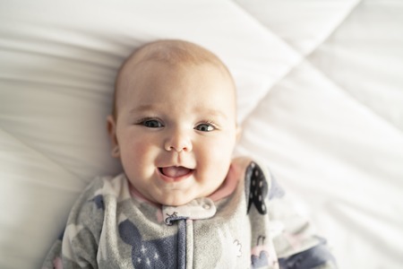 A Cute baby girl on a white bed at homeの写真素材