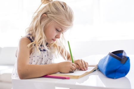 little girl drawing in the kitchen tableの写真素材