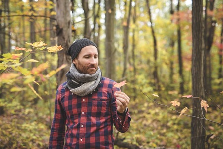 Confident and handsome. Handsome young man in the background and orange fallen leaves on the floorの写真素材