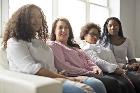 Two family Friends Sitting On Sofa Togetherの写真素材