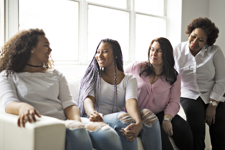 Two family Friends Sitting On Sofa Togetherの写真素材