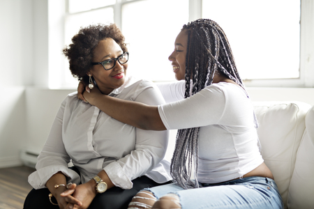 affectionate mother and daughter sitting on sofaの写真素材