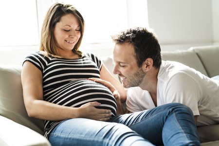 A pregnancy and people concept happy man pregnant woman at homeの写真素材