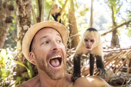 men tourist makes selfie self portrait with monkeyの写真素材
