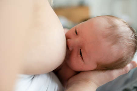 mother in her bedroom breastfeed her baby.