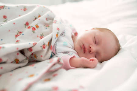 A Sweet newborn baby girl sleeping in white bed