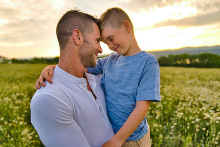 happy family of father and child on field at the sunset having funの写真素材