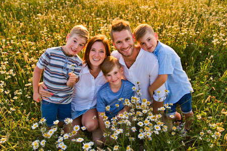 Happy family on daisy field at the sunset having great time together