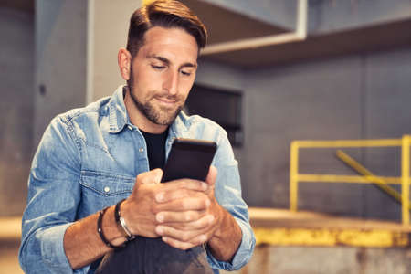 man on the basement background in the city using cellphoneの写真素材