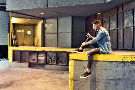 man on the basement background in the city using cellphone