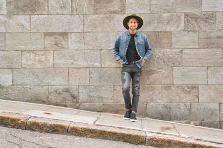 casual young man standing by a concrete wall