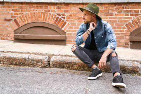 casual young man standing by a brick ballの写真素材