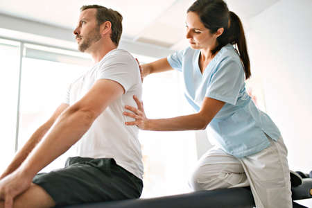 physiotherapist doing treatment with patient in bright officeの写真素材