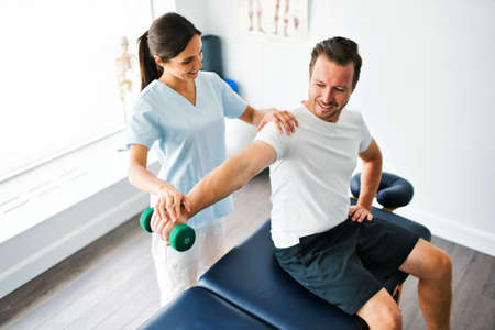 physiotherapist doing treatment with patient in bright officeの写真素材