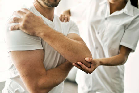 physiotherapist doing treatment with patient in bright officeの写真素材