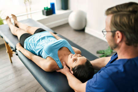 Male Physical Therapist Stretching a Female Patient neck