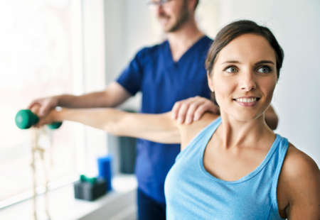 Male Physical Therapist Stretching a Female Patient Slowly.の写真素材