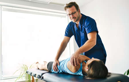 Male Physical Therapist Stretching a Female Patient Slowly.