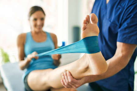 Male Physical Therapist Stretching a Female Patient with elastic