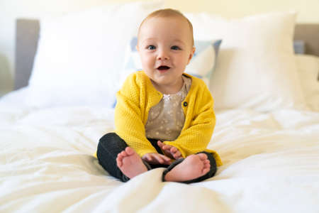 Nice and cute Baby sit in white bedding.の写真素材