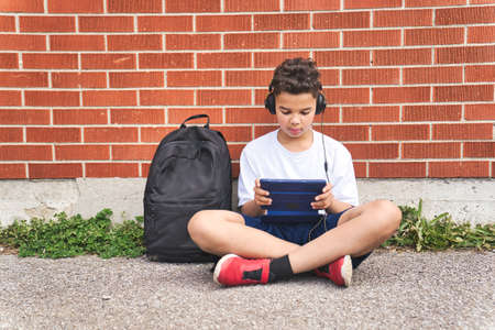 teenager boy listening and play tablet at school playground