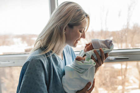 Mother with her newborn baby at the hospital in front of a windowの写真素材