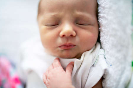 A Sweet newborn baby girl sleeping in white bedの写真素材