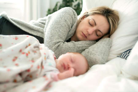 A mother and baby sleeping together in a bedroomの写真素材