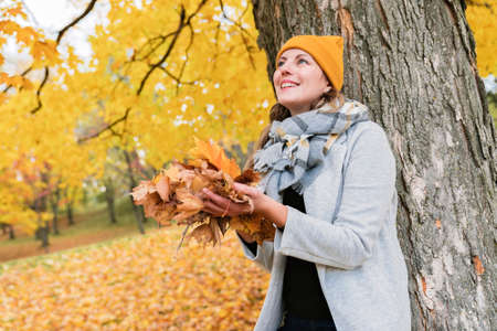 Young woman in autumn leaves and fall yellow maple garden background