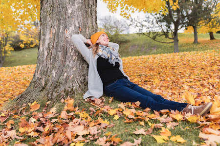 Young woman in autumn leaves and fall yellow maple garden background