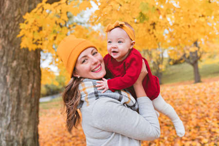 Baby daughter and her mother in the autumn season in parkの写真素材