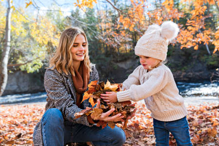 Little girl and her mother playing in the autumn park