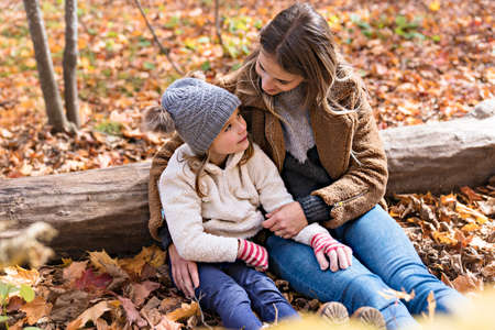 Little girl and her mother playing in the autumn park
