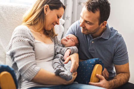 Parents and Baby having wonderful time sit on chair one the bedroomの写真素材