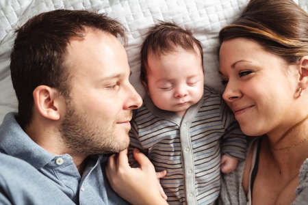 A beautiful couple with newborn Baby on bed.の写真素材