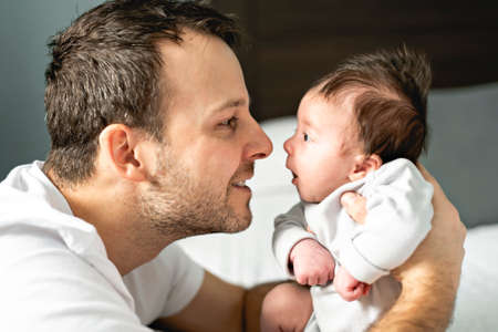 Father and newborn baby closeup on the bed.