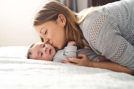 Mom and Baby having wonderful time on bed on the morningの写真素材