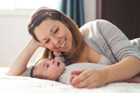 Mom and Baby having wonderful time on bed on the morningの写真素材