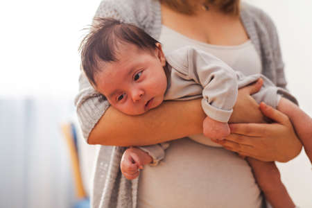Mom holding Baby one the bedroom. The baby is going to sleep