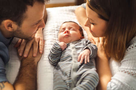 A beautiful couple with newborn Baby on bed.