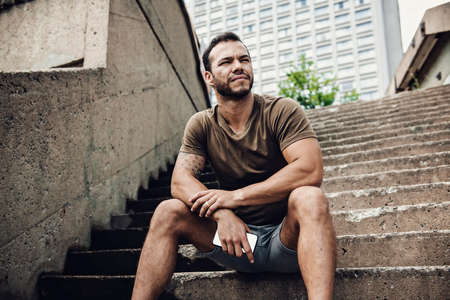 A sexy man outside in a city background holding cellphoneの写真素材
